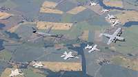 A C-130, eight fighter jets and a B1 fly in formation.