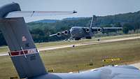 A transport aircraft is landing on a runway.