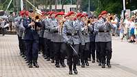 Soldatinnen und Soldaten marschieren musizierend durch die Kaserne.