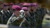 Soldaten mit weinroten Baretten stehen in Formation