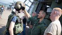 Ein Soldat legt einem Besucher einem Pilotenhelm an am Tag der Bundeswehr