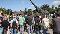 Ein Soldat spricht vor einer Panzerhaubitze 2000 zu Besuchern am Tag der Bundeswehr