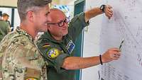 Oberstabsfeldwebel (OA) Nico W. zeigt einem amerikanischen Soldaten etwas auf der Flugplatz-Karte