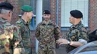 Vier Soldaten stehen vor einem Kasernengebäude zusammen und sprechen miteinander.