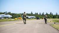 Zwei Wachsoldaten gehen über den Rollweg während der Streife an A-10 Kampfjets vorbei