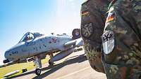 Zwei Soldaten halten ihre Patches in die Kamera, im Hintergrund sieht man einen A-10 Kampfjet