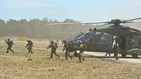 Soldaten steigen aus zwei Hubschraubern aus und rennen in ihre Stellungen.