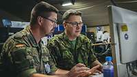 Zwei Soldaten sitzen vor einem Monitor und besprechen sich