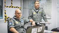 Two soldiers in flight suits at a computer.