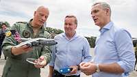 The Air Force Chief of Staff, the NATO secretary general and the defense minister look at an A400M model.