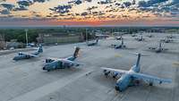 More than twelve transport aircraft are parked at the airfield in Wunstorf at dawn.