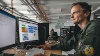 A soldier in pilot suit of the Czechs sits in front of a PC and prepares for his mission.