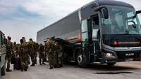 Deutsche Soldaten stehen an einem litauischen Reisebus.