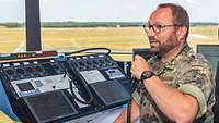 An air traffic controller is sitting in the tower of Lechfeld Air Base and communicates via radio.