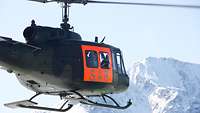 Ein Hubschrauber vom Typ Bell UH-1D mit der Aufschrift „SAR“ fliegt im Gebirge