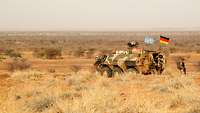 Soldaten auf Patrouille stehen am Transportpanzer Fuchs in der Wüste