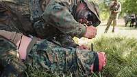 Ein Soldat notiert die Zeit, zu der er die Blutung eines Beinstumpfes durch Abbinden gestoppt hat