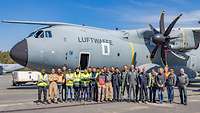 Viele Menschen auf einer Betonfläche mit einem Flugzeug dahinter