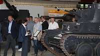 Ein schwarzlackierter Panzer steht in einem Museum, Besucher laufen daran vorbei.