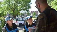 Zwei weibliche Militärbeobachter im Gespräch mit einem Darsteller in fremdländischer Uniform