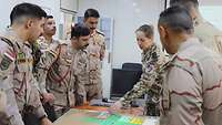 Deutsche Soldatin erläutert irakischen Soldaten verschieden farbige Zettel auf einer Pinnwand