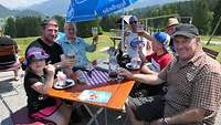 Familienangehörige machen Rast auf der Dorne Alpe und genießen Speisen und Getränke