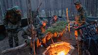 Soldaten sitzen um ein Lagerfeuer