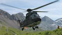 Zu sehen ist ein Schweizer Hubschrauber über grüner Landschaft