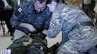 Eine Soldatin und ein Soldat beim Training an der Trauma-Simulationspuppe.