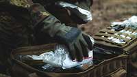 Ein Soldat packt einen Rucksack mit Medikamenten.
