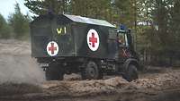 Ein Krankentransportwagen mit Rotem Kreuz auf weißen Grund im Wald