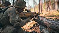 Zwei Soldaten knien parallel zueinander auf dem Waldboden. Einer von ihnen hat ein Maschinengewehr MG5 in der Hand.