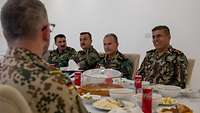 Vier kurdische und ein deutscher Soldat sitzen am gemeinsamen Mittagstisch.