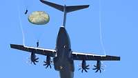 Am blauen Himmel fliegt ein Flugzeug, während Soldaten herausspringen.