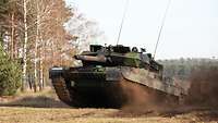 A main battle tank crosses a sandy patch and seems to take off at full speed