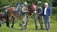 Bundespräsident Steinmeier spricht mit zwei Soldaten, die neben einem Muli stehen