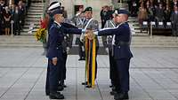 Soldaten stehen auf dem Paradeplatz und legen mit der Hand an der Truppenfahne ihren Eid ab