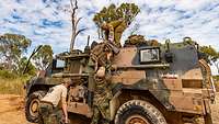 Mehrere Soldaten beladen ein militärischen Fahrzeug mit ihrer Ausrüstung.