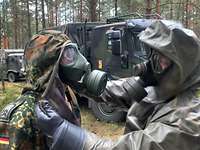 Ein Soldat unterstützt beim Anlegen der persönlichen ABC-Schutzbekleidung.