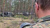 Ein Soldat beobachtet ein Übungsszenario in einem Wald