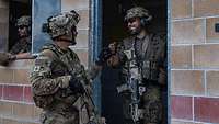 Zwei Soldaten stehen am Eingang eines Gebäudes und halten die Fäuste aneinander.