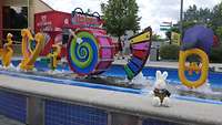 Ein Hase sitzt vor Musikinstrumenten die aus Lego nachgebaut sind an einem Wasserspielplatz.