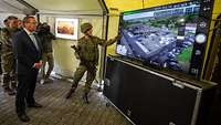 Minister Pistorius steht vor einem Bildschirm in einem Zelt. Ein Soldat zeigt ihm einen Drohnenflug.