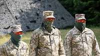 Drei ukrainische Soldaten stehen vor einem Zelt