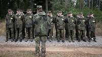 Eine Gruppe Frauen in Flecktarn tritt in Formation vor einer Soldatin als Gruppenführerin an