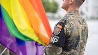 Ein Soldat hisst eine Regenbogenpflagge 