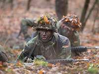 Soldaten gleiten mit dem Gewehr G36 über den Waldboden.