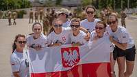 Eine Gruppe von Soldatinnen hält eine polnische Flagge hoch