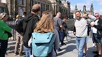 Mehrere Personen stehen vor einem älteren Gebäude in Dresden. 