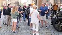 Eine größere Gruppe Menschen steht vor der Dresdner Frauenkirche. 